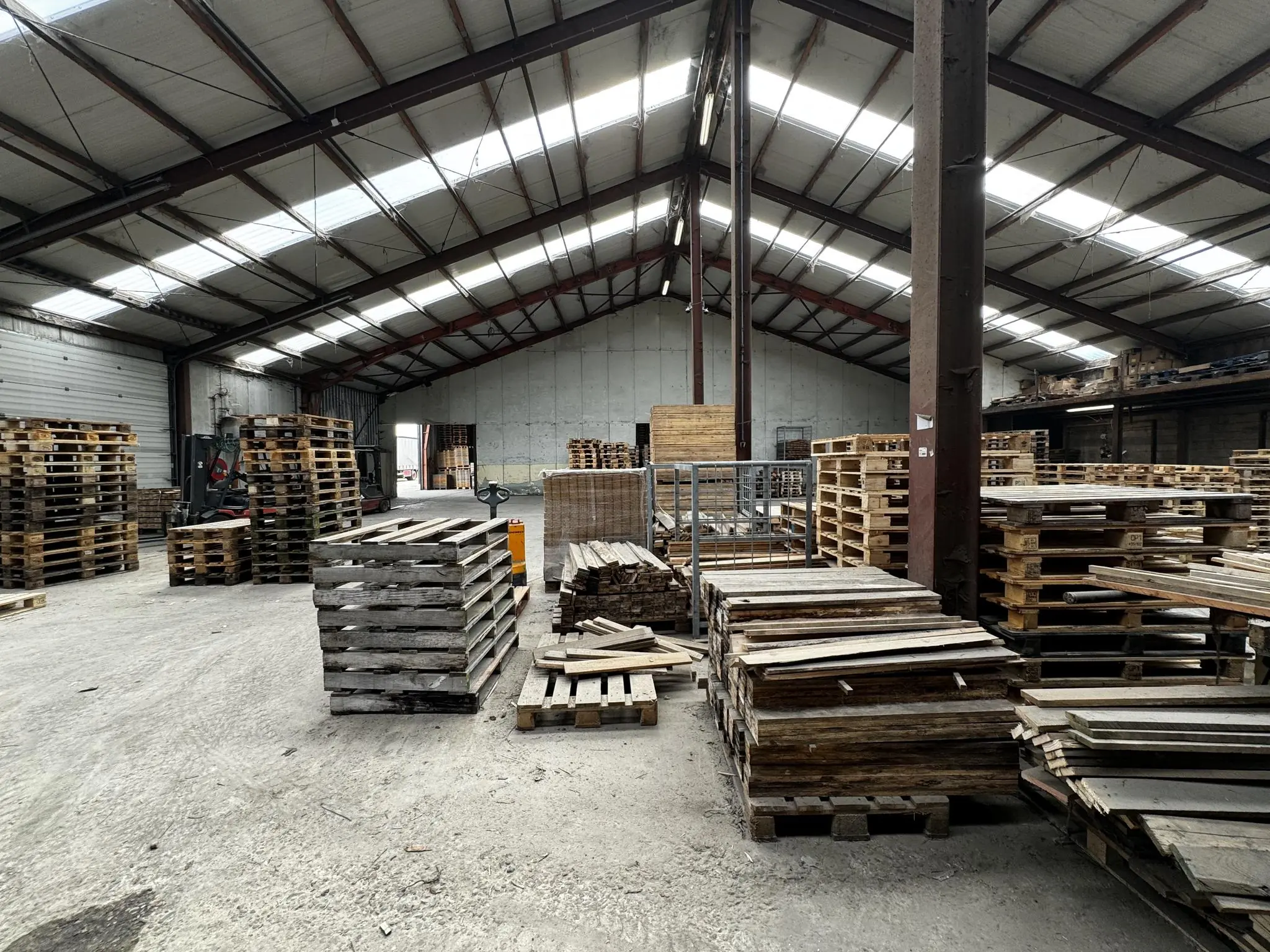 Industriële loods aan de Graaf van Lynden van Sandenburgweg met stapels houten pallets en planken.